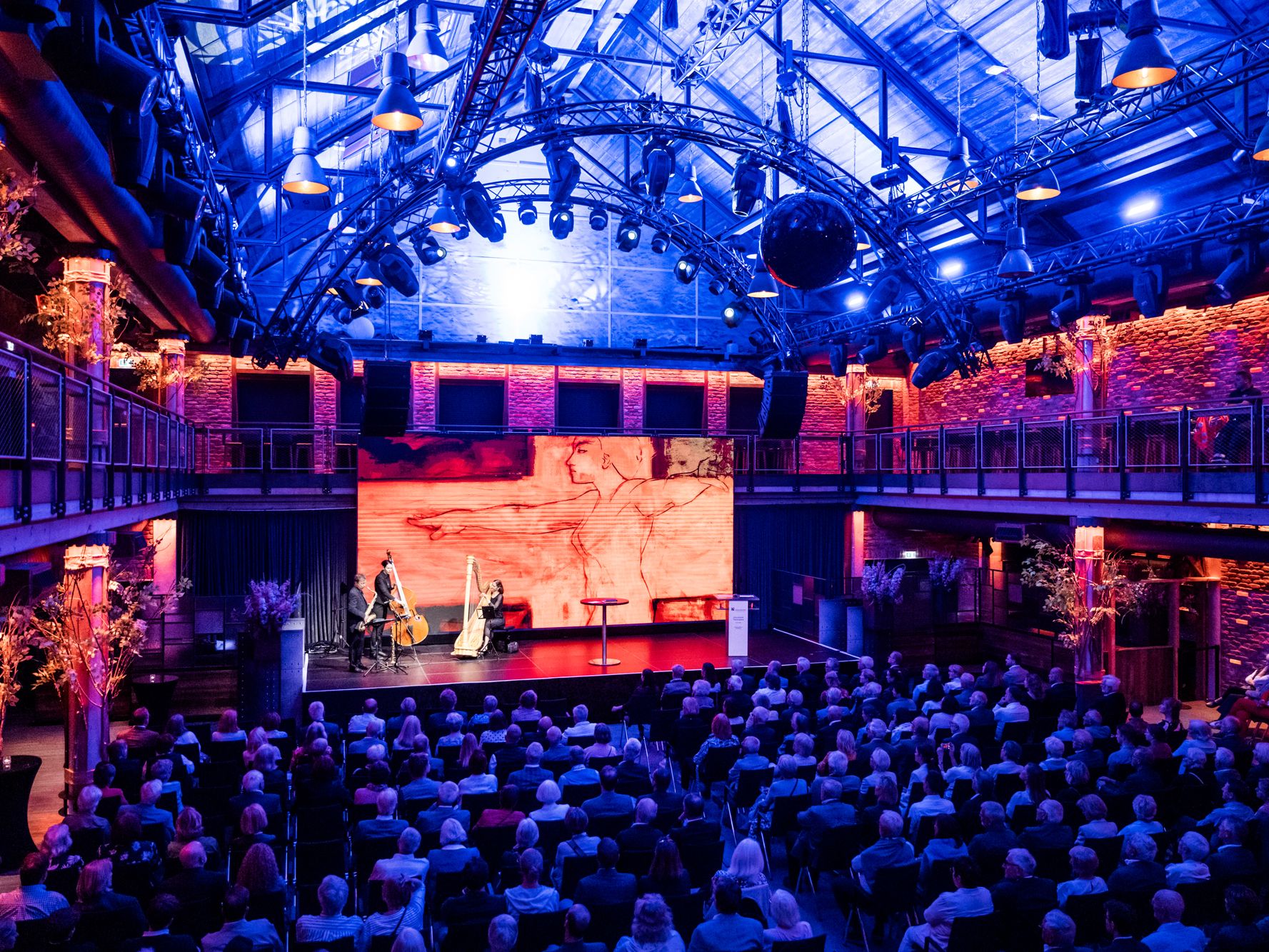 Blick von oben auf den stimmungsvoll beleuchteten Ballsaal mit Zuschauerraum und Bühne