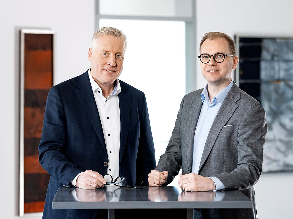 Vorstand Andreas Stahmeyer und Neu-Vorstand Daniel Tellkamp stehen am Pult und schauen in die Kamera