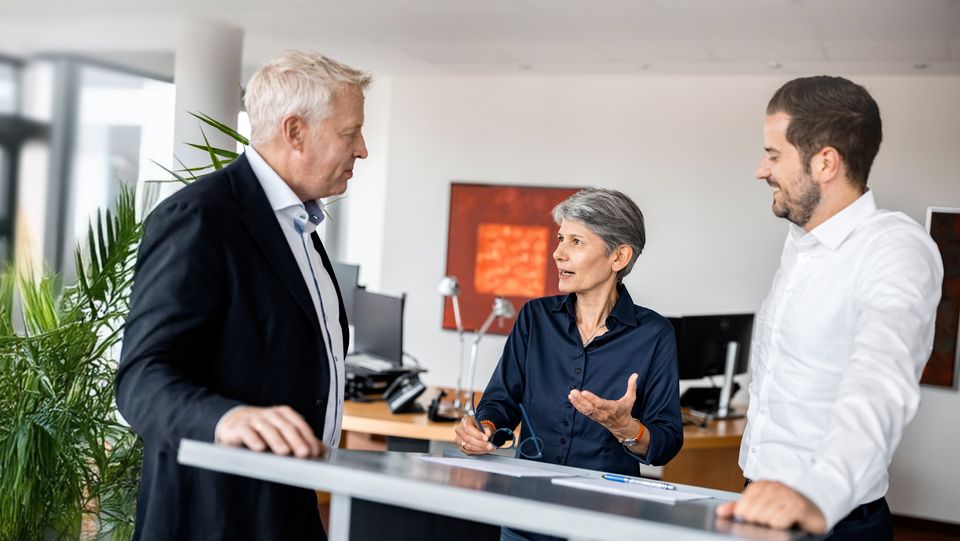 Drei COLLEGIUM Mitarbeiter*innen an einem Stehtisch unterhalten sich
